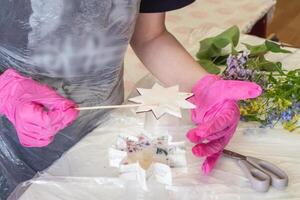 Hand is in motion, selective focus. Art process of pouring epoxy resin into a wooden toy. Technology process of creating a painting in style resin art, works with epoxy in studio, makes a wooden stand photo