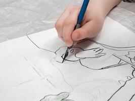 Hand with a pen draws lines with ink. Schoolboy calligraphy performs a task at the workplace. Concept of children's education, teaching knowledge, skills and abilities. photo