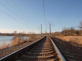 Perspective of rounded rails. Railway track turns and twists between out of focus hills background. Empty rounding and turning single track of railways. Empty railway track, single rail. photo