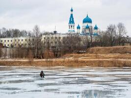 Dangerous fishing on wet winter ice. Fisherman on wet melting ice. Dangerous thin ice on the lake. photo