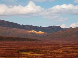 Bright narrow ray of sun on a dark mountain slope. photo