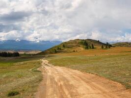 Way to the distance, way over the hill to the sky. Dirt road through the field. Field with a dirt road. photo