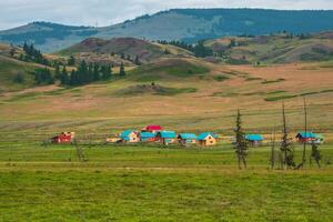Modern countryside in highlands. Collective camping to the distance, tourist complex, wooden guest houses against the background of green hills. Farmstead in the steppe. photo
