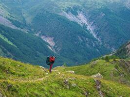 Photographer with a large camera takes pictures of a beautiful mountain landscape. Photographer with a large backpack on a narrow mountain path. photo