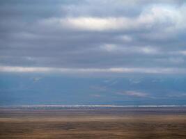 Thin line of a distant city in the steppe under a blue cloudy sky. Altai steppe. photo