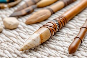Traditional Native American spear with stone tip and leather bindings displayed alongside various tools and artifacts on a textured surface photo