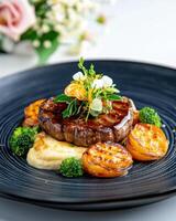 Gourmet dish featuring tender beef filet with seasonal vegetables and a rich sauce elegantly presented on a navy ceramic plate photo