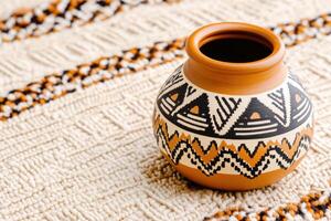 Traditional Native American pottery with geometric patterns displayed on a woven blanket photo