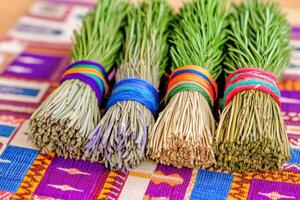 Close-up of colorful sage and cedar bundles beautifully arranged on a patterned Native American cloth backdrop photo