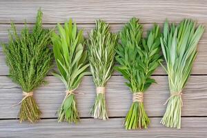 Collection of Native American herbs including sage, sweetgrass, and cedar arranged in bundles on a wooden surface illuminated by natural light photo
