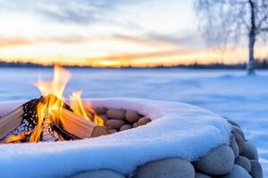 Cozy outdoor fire crackles under twilight sky amidst snow-covered logs and frosted branches creating a warm atmosphere photo