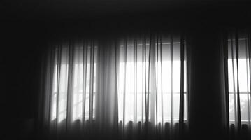 A black and white photo of a window with curtains