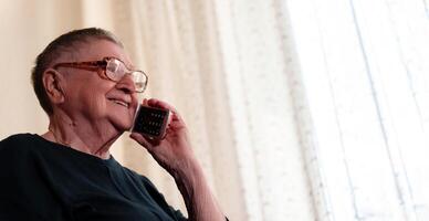 Senior citizen uses a handheld gadget to connect with family, demonstrating how technology can enhance intergenerational relationships photo