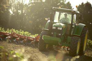 Farmer operating tractor in field at sunset with plow attachment photo