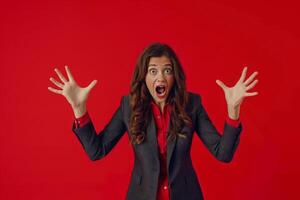 Excited woman in business attire expresses surprise on vibrant red background photo