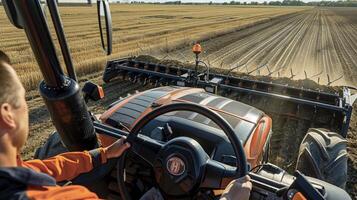 Farmer operating modern tractor in vast harvested field photo