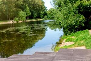 Tranquil river scene with lush greenery and wooden deck photo