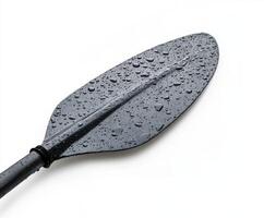 Raindrops glisten on a black kayak paddle resting against a white background during a rainy day photo