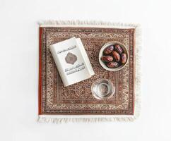 Exquisite arrangement of dates, a glass of water, and a book on a patterned cloth in a tranquil setting photo