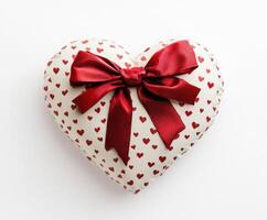 Heart-shaped gift wrapped in red ribbon sits against a light background for a romantic occasion or celebration photo