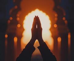 Hands in prayer position silhouette against a stunning sunset backdrop in a serene temple setting photo