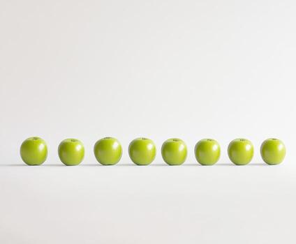 Green apples arranged in a straight line on a minimalist background creating a fresh and vibrant look photo