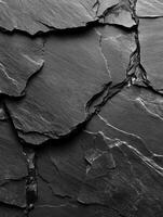 Dark, textured slate rock surface with distinct cracks and layers highlighting natural geological features photo
