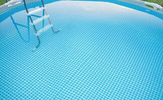 Frame pool with clean water for swimming and a ladder on the grass in summer. photo