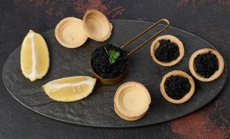Black sturgeon caviar and empty round tartlets on table, top view. photo