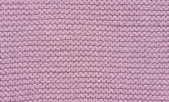 Knitted fabric made of pink wool threads, pigtail pattern, full frame. photo