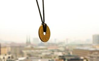 Lucky japanese 5 yen coin necklace displayed with a blurred foggy Berlin skyline in the background, symbolizing good fortune and cultural heritage. Selective focus. Copy space 1 photo