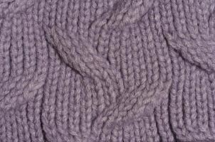 Knitted fabric made of purple wool threads, pigtail pattern, full frame. photo