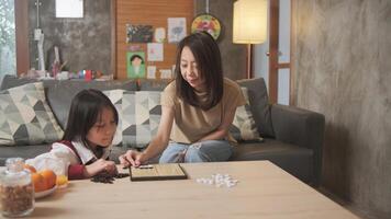 Asian family, mum, and kid fun playing Go board game on table in home living room together with love and cheerful, happy weekend relaxing hobby of child and parent, concentrate and compete. photo
