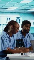 Vertical African american general practitioner leading a healthcare team in a cabinet, analyzing MRI imaging results and providing accurate diagnosis and effective treatment. Medical facility. Camera B. video