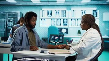 African american medic monitoring pulse and heartbeat with a smartwatch for a patient, looking at her wrist watch fitness tracker accessory during checkup. Heart rate measurement. Camera B. video