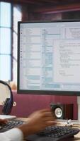 Vertical Engineer in home office looks at UI on computer monitor, typing and executing programming code. Panning shot of IT worker using coding application to write and test code in modern apartment, camera A video