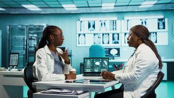 Black medical staff and patient discussing diagnostic feedback and records, emphasizing expertise and data driven decision making. Young adult listens to professional advice for wellness. Camera B. video
