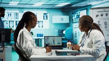 Physician calling the expert practitioner on conference with a patient, creating a telehealth consultation for a second opinion. Medical staff using high tech equipment at clinic. Camera B. video