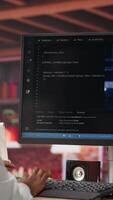 Vertical Admin doing maintenance on artificial intelligence neural networks computerized model, listening music. Tech support specialist wearing headphones doing checkup on AI systems, camera B video