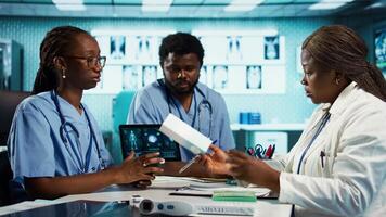 Physician and assistants in a medical cabinet discussing about drugs and painkillers to recommend to patients, providing accurate expert advice. Improving the medical services. Camera B. video