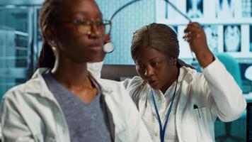 General practitioner uses a stethoscope to consult patient with illness, ensuring normal function of lungs and heartbeat. African american girl with a respiratory problem at checkup. Camera A. video