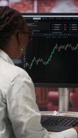 Vertical Day trader using PC to purchase and sell stocks, reading files, aiming to capitalize on market trends and fluctuations. Investor tracking stock forex trends on computer monitor, camera B video