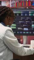 Vertical Teleworking computer scientist at home using PC to develop artificial intelligence self learning algorithms. African american woman working with AI machine learning software on PC, camera B video