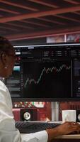 Vertical Day trader using PC to purchase and sell stocks, reading files, aiming to capitalize on market trends and fluctuations. Investor tracking stock forex trends on computer monitor, camera A video