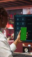 Vertical Woman uses green screen phone, doing videocall in front of PC screen with AI LLM chatbot answering prompt. Person uses large language model program during teleconference on mockup smartphone, camera A video