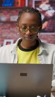 Vertical Portrait of happy teleworker using laptop in home office to write emails. Joyful remote worker typing on notebook, composing documents in order to deliver finalized project paperwork, camera B video