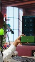 Vertical Woman seated at desk using isolated screen mobile phone to follow tutorial on AI LLM chatbot software. African american person uses mockup smartphone in apartment and GPT program on computer, camera A video