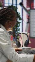Vertical Engineer in home office looks at UI on computer monitor, typing and executing programming code. Panning shot of IT worker using coding application to write and test code in modern apartment, camera B video