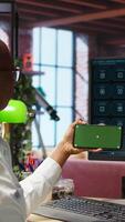 Vertical Woman using green screen smartphone to learn how to use AI LLM chatbot on computer screen in home office. Person watches tutorial on mockup phone about artificial intelligence chatbots, camera A video