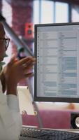Vertical Jolly engineer in home office working on computer, dancing at desk in celebration after successfully executing code. IT worker wearing headphones happy after finishing compiling code, camera B video